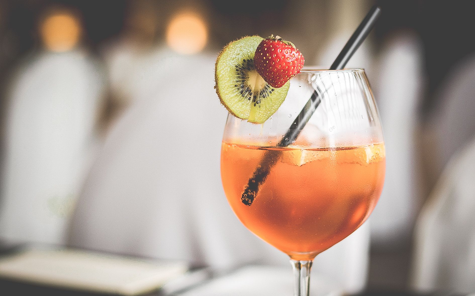 Un cocktail agrémenté de fraises et de kiwis, servi dans un verre à pied.