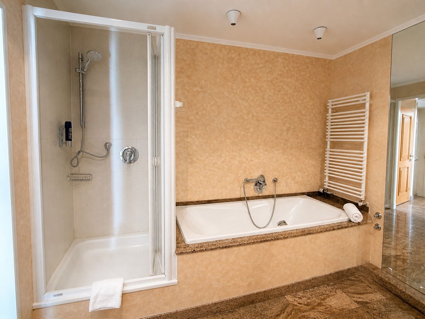 Een badkamer met een douche, bad en handdoekrek.
