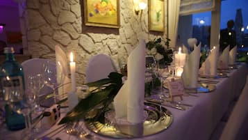 Una tavola imbandita per una cena formale, con candele, bicchieri e una carta del menu.