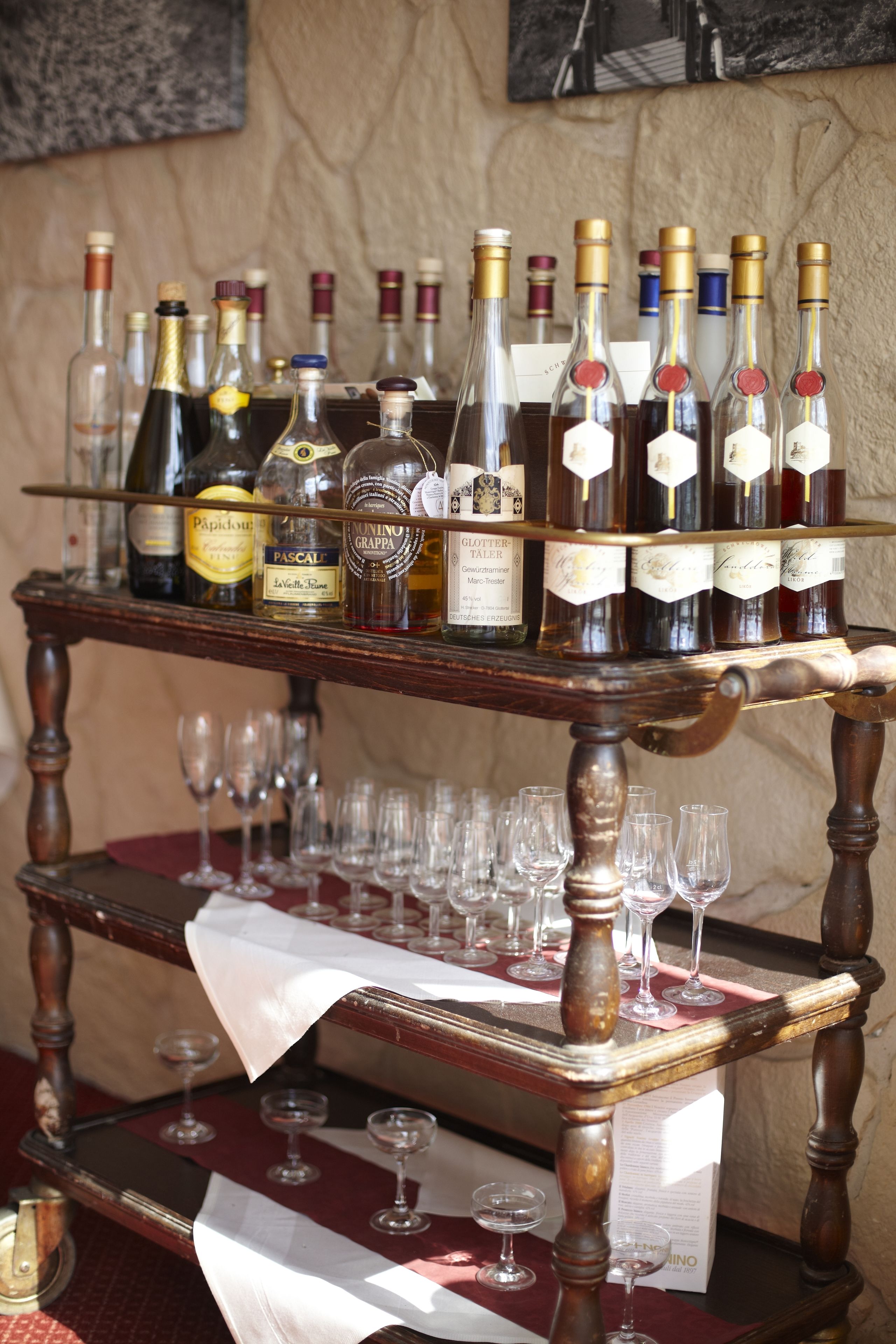 A wooden wine rack with multiple bottles and glasses.