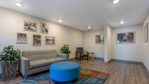 Un hall d’entrée moderne avec un canapé, un pouf et des fauteuils, un plancher en bois et des œuvres d’art murales.