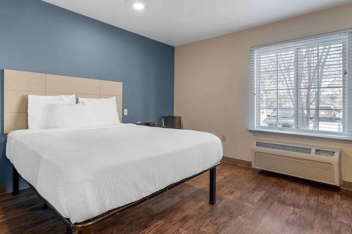 A bedroom with a bed, a heater, and a window with blinds.