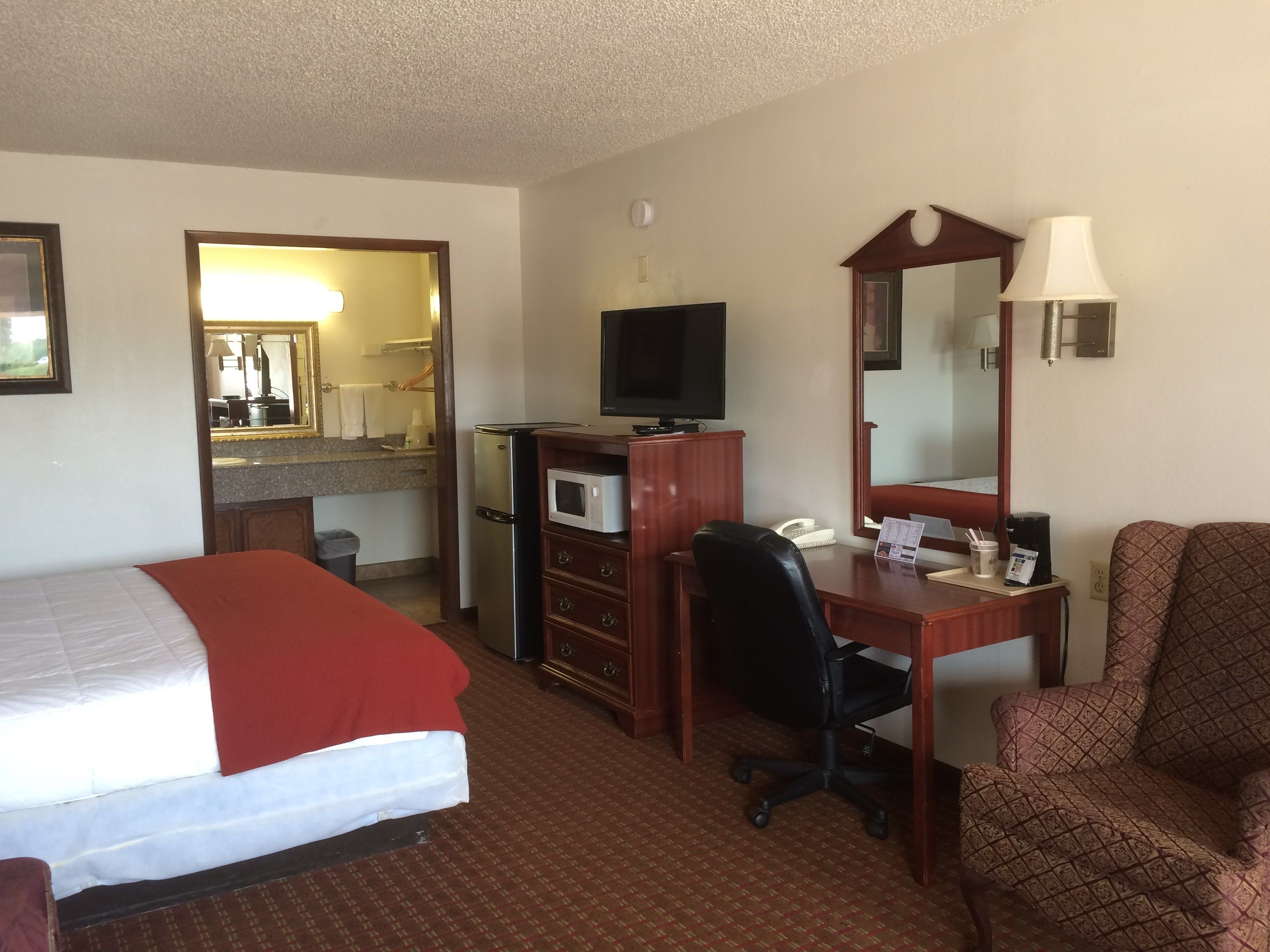 Une chambre d’hôtel équipée d’un lit, d’un bureau, d’une chaise et d’une kitchenette.