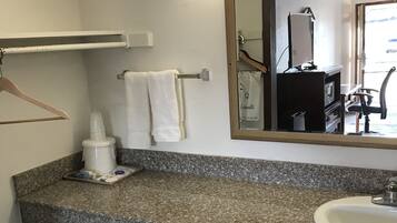 Un baño con encimera de granito, lavabo, espejo, toallero y cubo de basura.