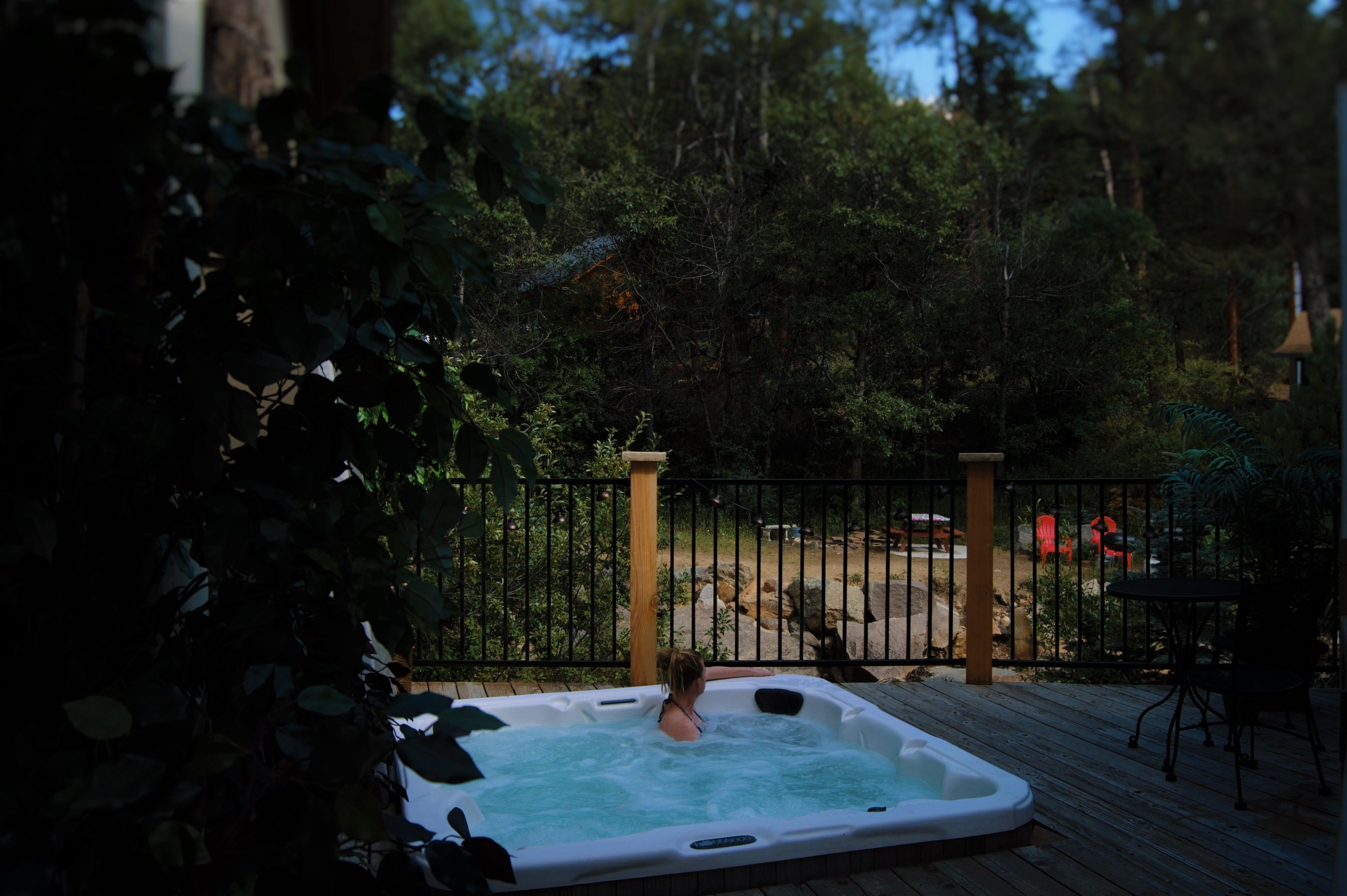 A hot tub on a wooden deck with a view of a forested area.