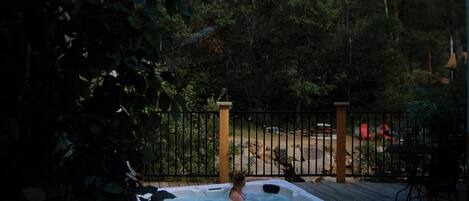 A hot tub on a wooden deck with a view of a forested area.