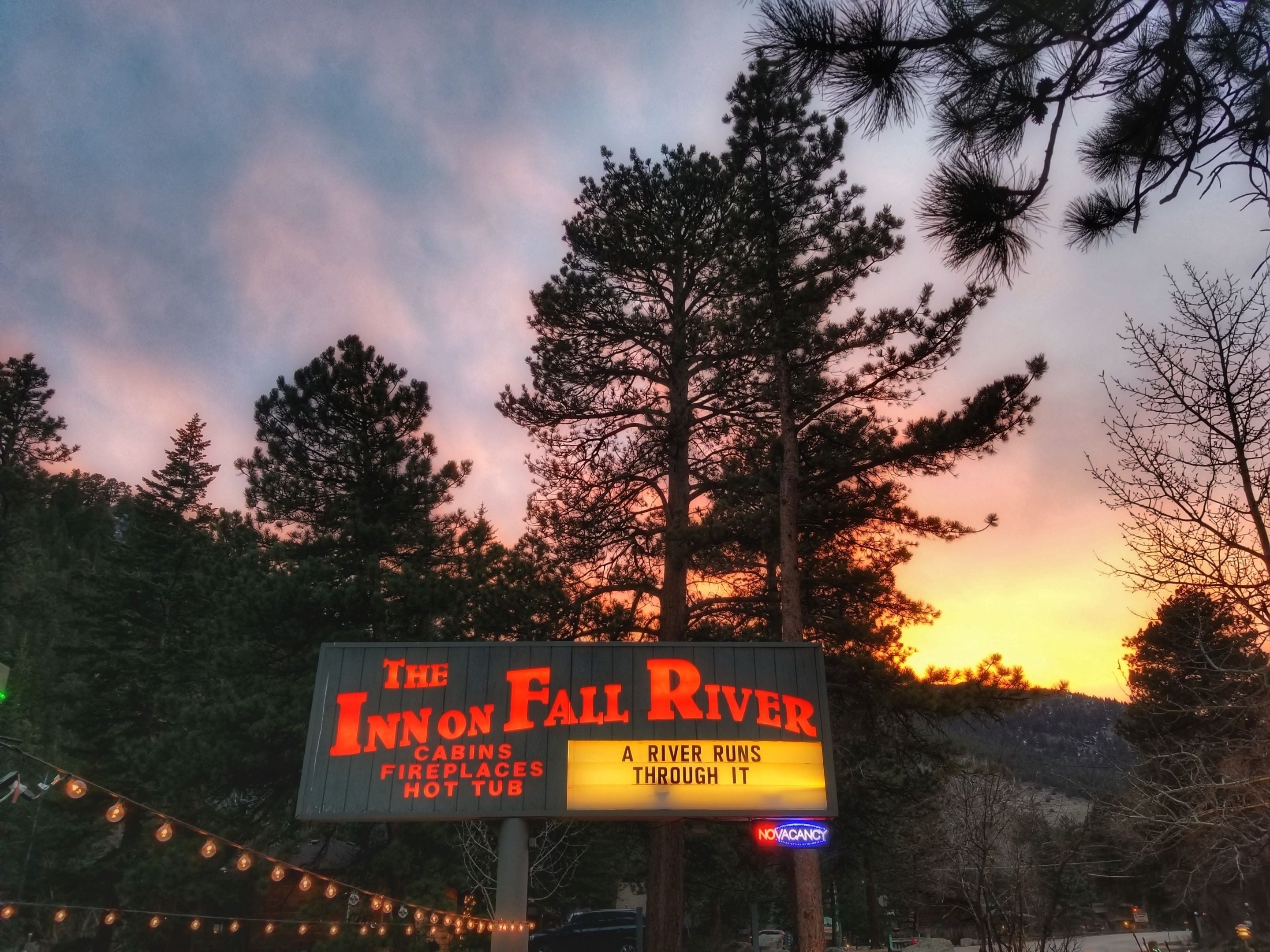 Señal de The Inn on Fall River con los servicios indicados: cabañas, chimeneas y un jacuzzi.