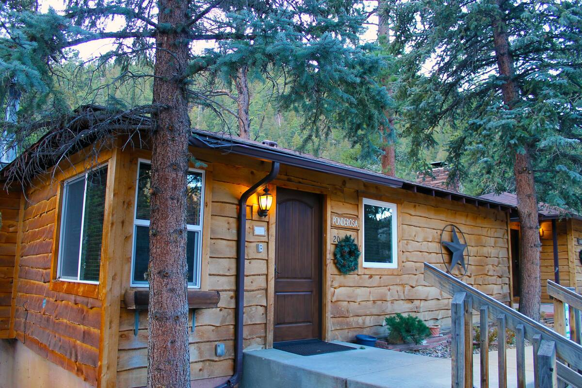 Une cabane en rondins avec une porte en bois, une fenêtre et une véranda.