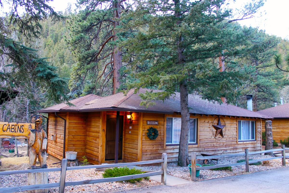 Une cabane rustique avec une façade en bois, une porte d’entrée, une fenêtre et une enseigne sur laquelle on peut lire « CABANES ».