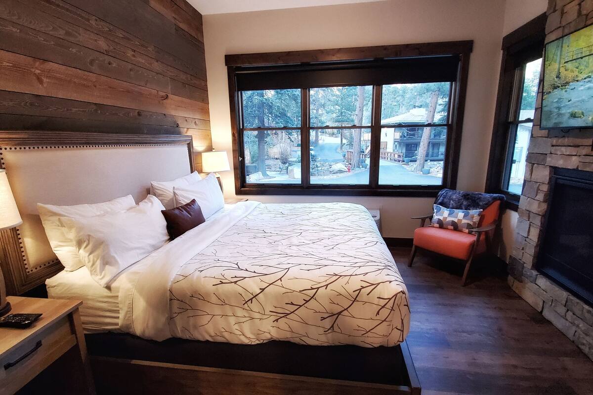 Une chambre à coucher comprenant un lit, une table de chevet, une chaise, une cheminée et une fenêtre donnant sur l’extérieur.