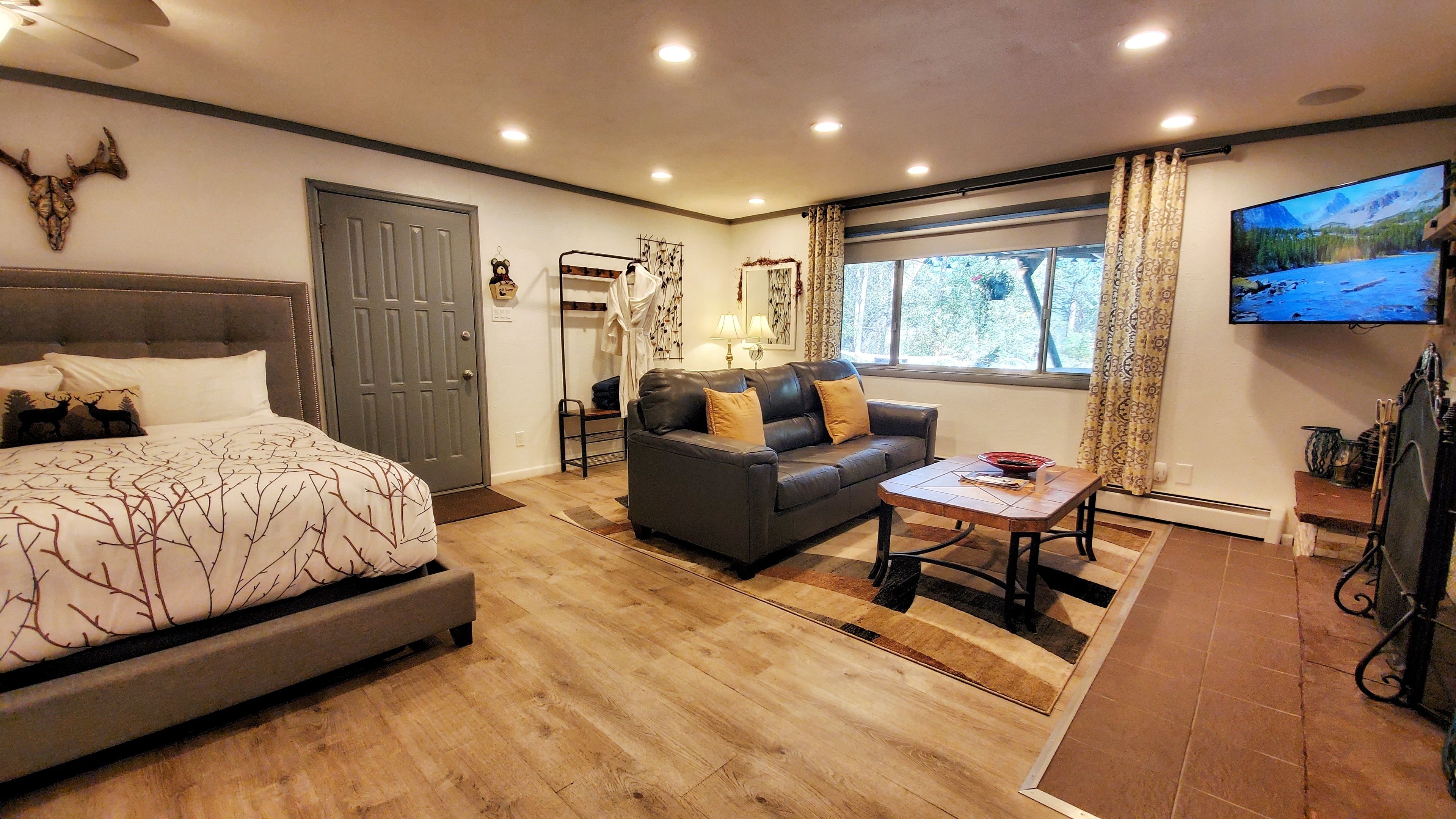 Una habitación luminosa con una cama, un sofá, una mesa de centro y un televisor.