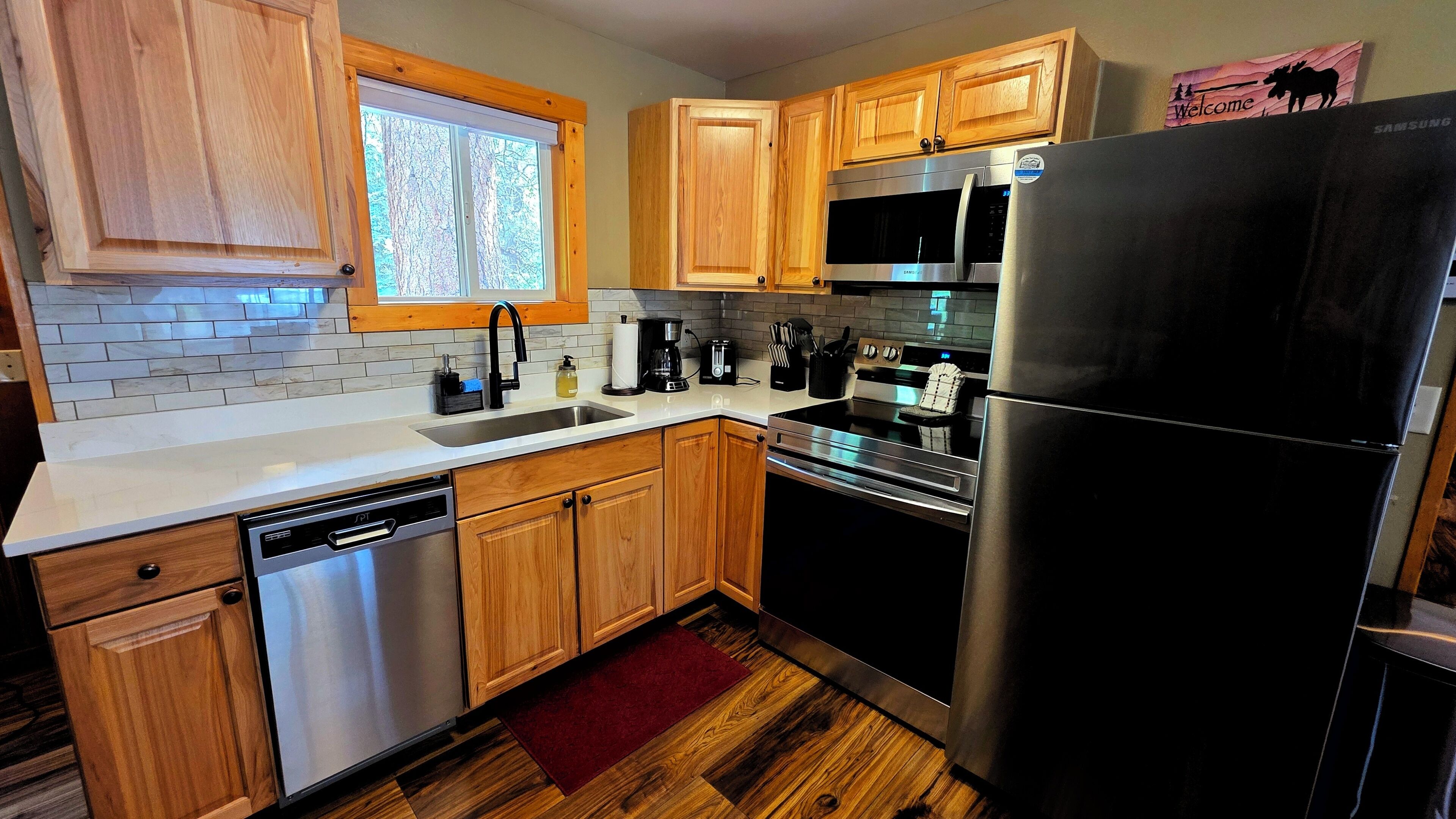 A kitchen with wooden cabinets, a stainless steel refrigerator, a microwave, and a dishwasher.