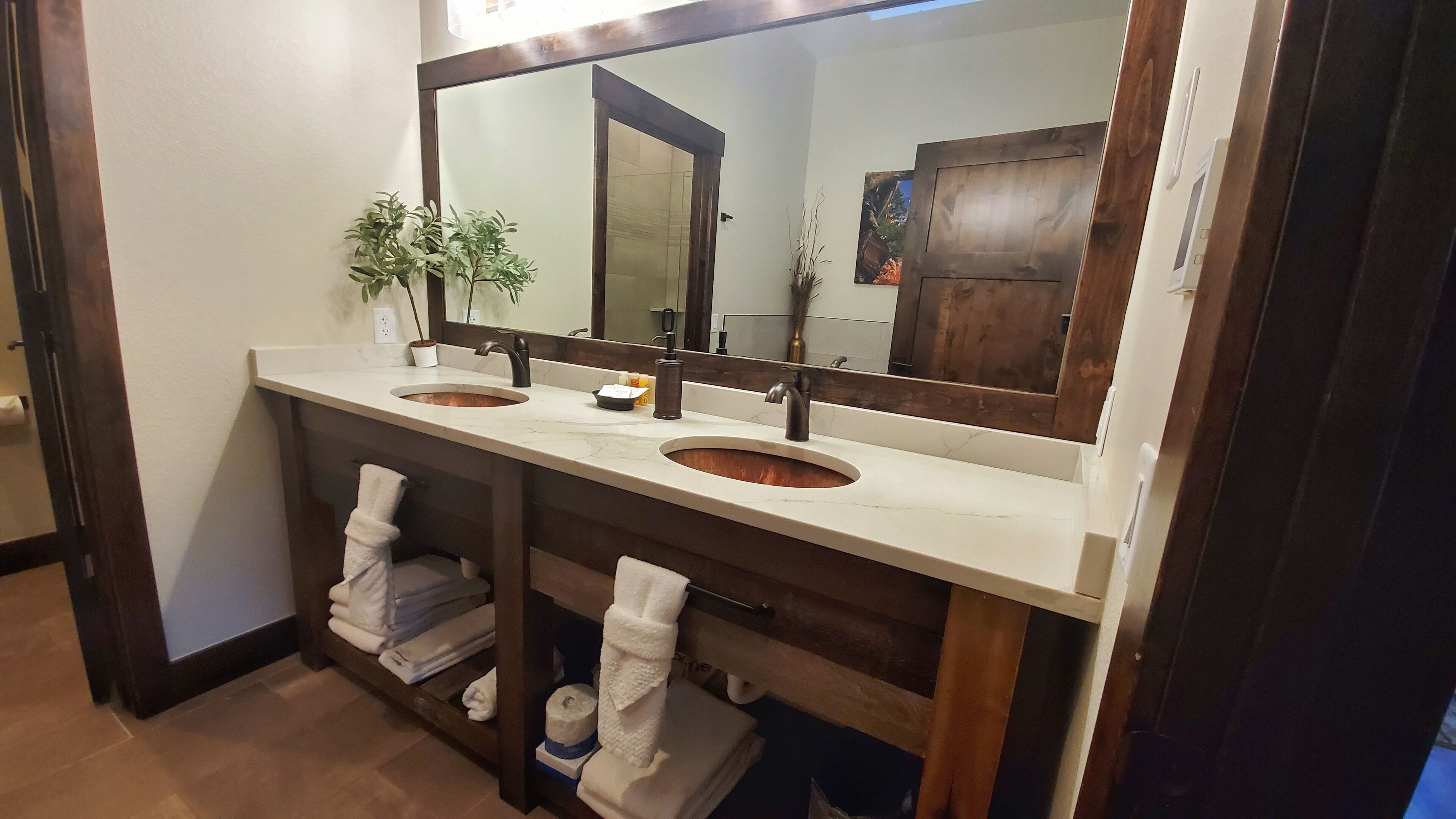 A bathroom with two sinks, a large mirror, and a towel rack with folded towels.