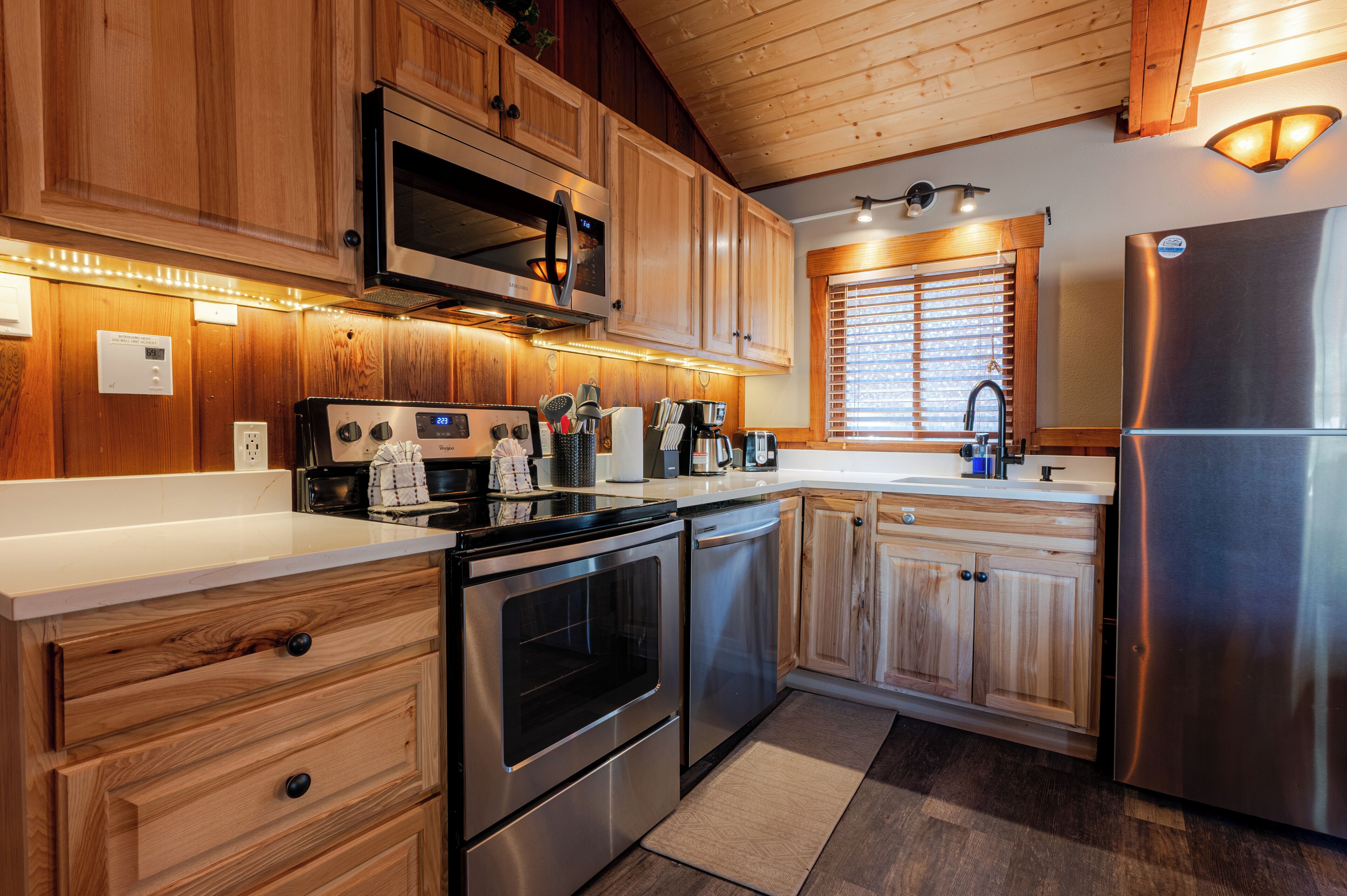 Una cocina moderna con armarios de madera, electrodomésticos de acero inoxidable y una ventana con persianas.