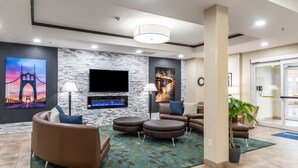 Una hall d'albergo moderna con parete in pietra, una televisione a schermo piatto, comodi posti a sedere e una grande finestra.