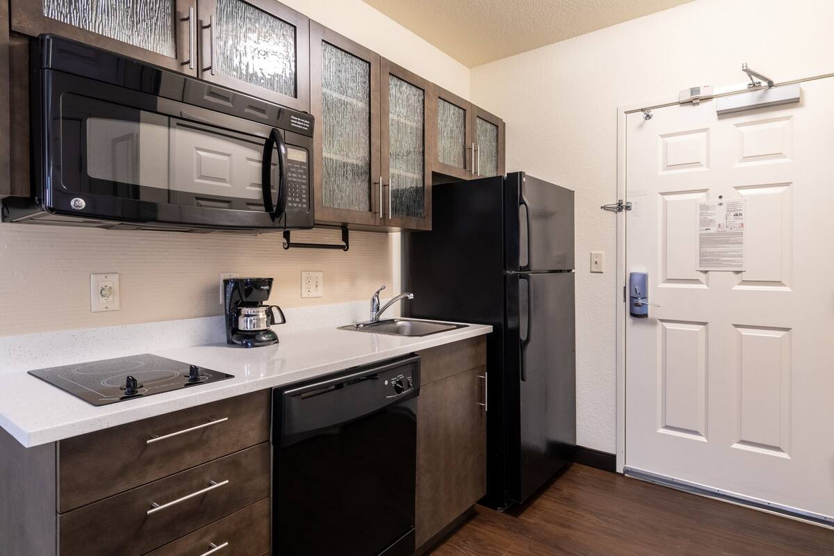 Una cocina equipada con lavavajillas, refrigerador, microondas y cafetera.