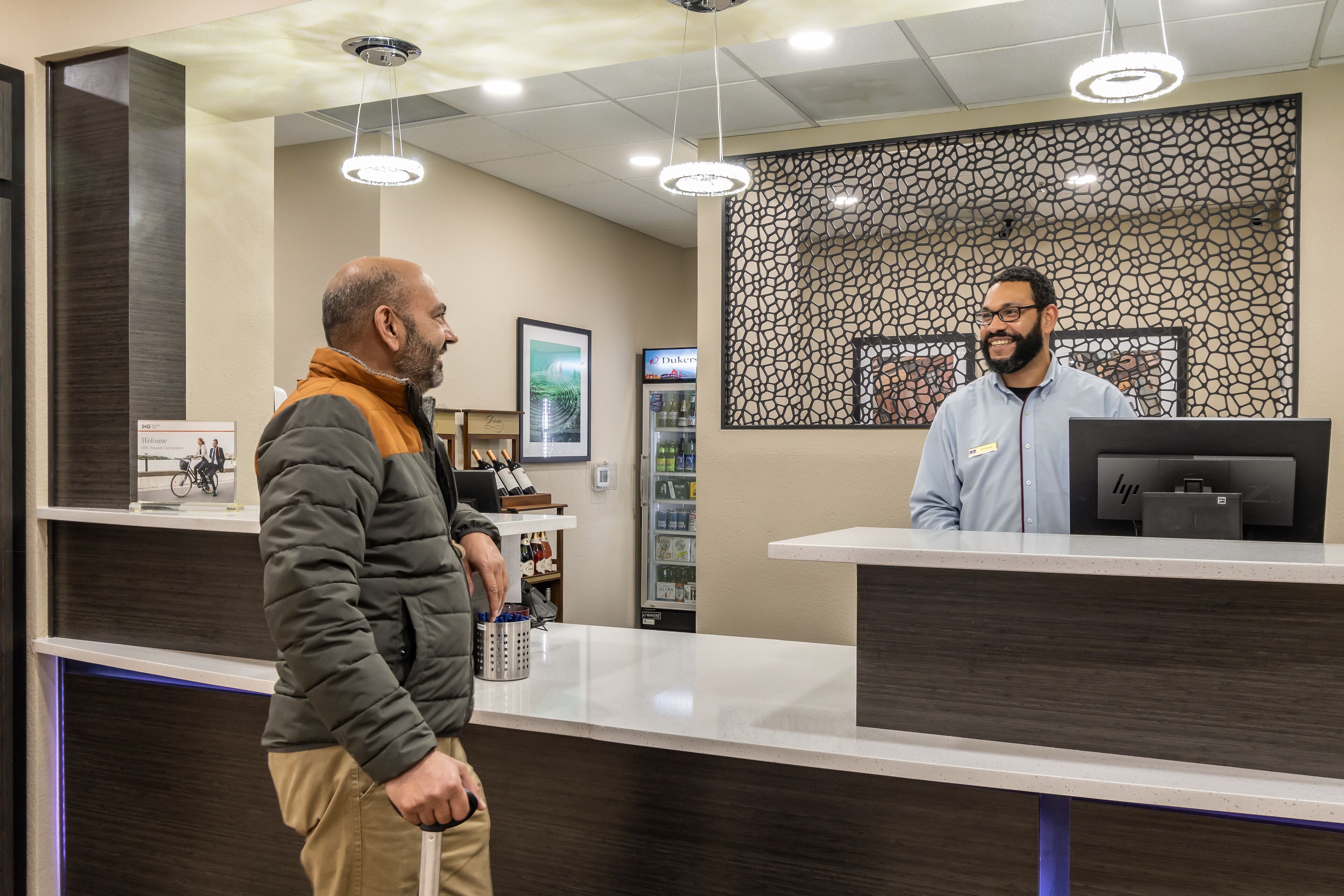 A reception area with a counter, a computer, and a decorative wall.