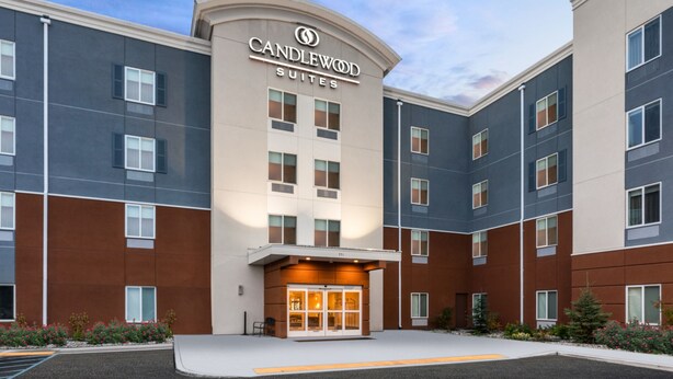 Un hotel moderno con un ingresso ben visibile, diversi piani e cielo sereno.