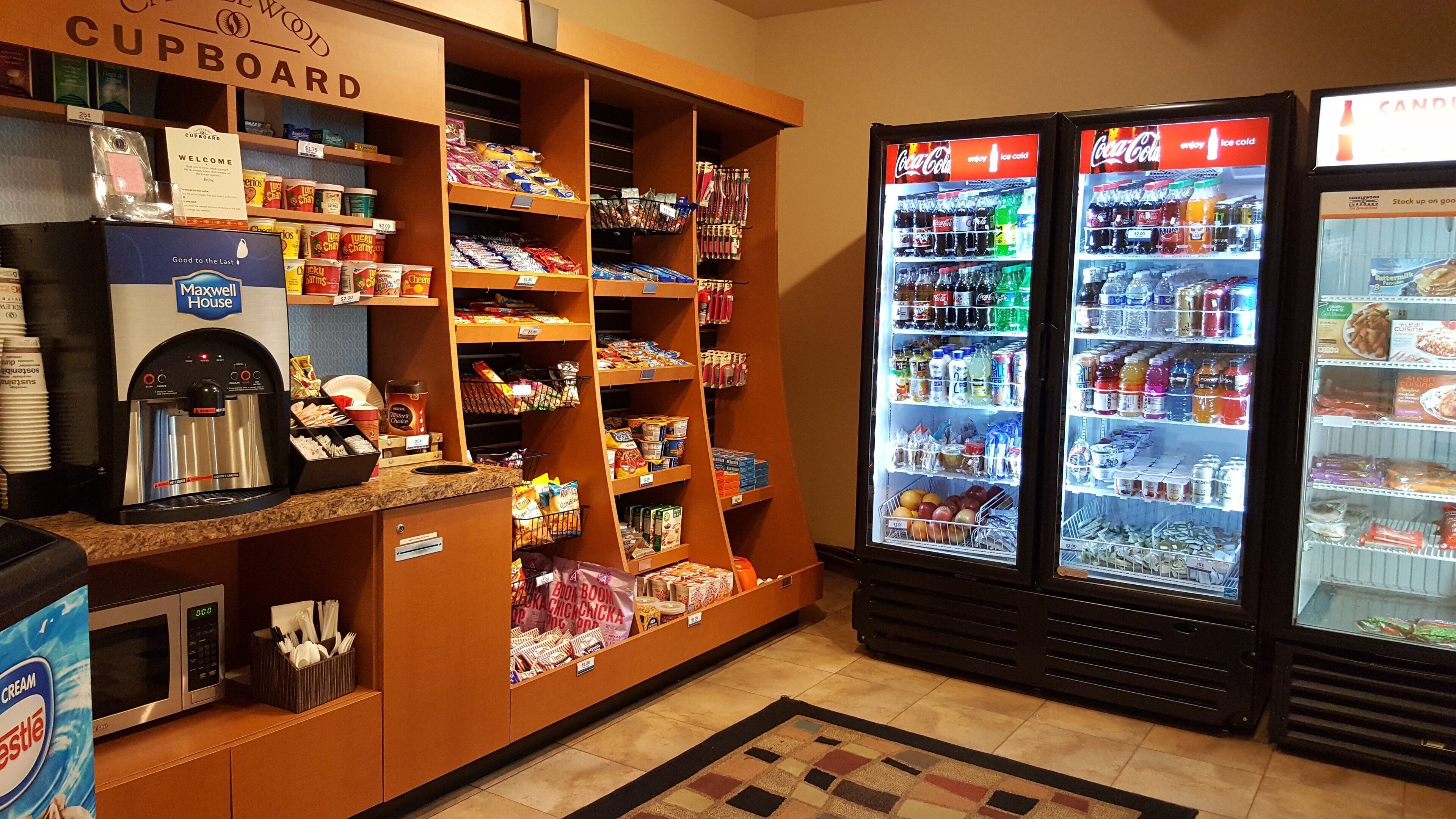 A self-service area with a coffee machine, snack dispensers, and refrigerated beverage dispensers.