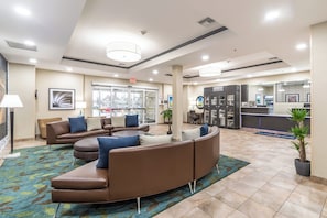 A hotel lobby with a curved brown sofa, a reception desk, and a coffee machine.