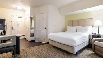 Habitación de hotel con cama, escritorio, silla, lámpara y puerta.