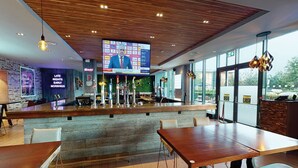 A modern restaurant with a bar area, wooden ceiling, and large windows. - Village Hotel Farnborough (Farnborough)