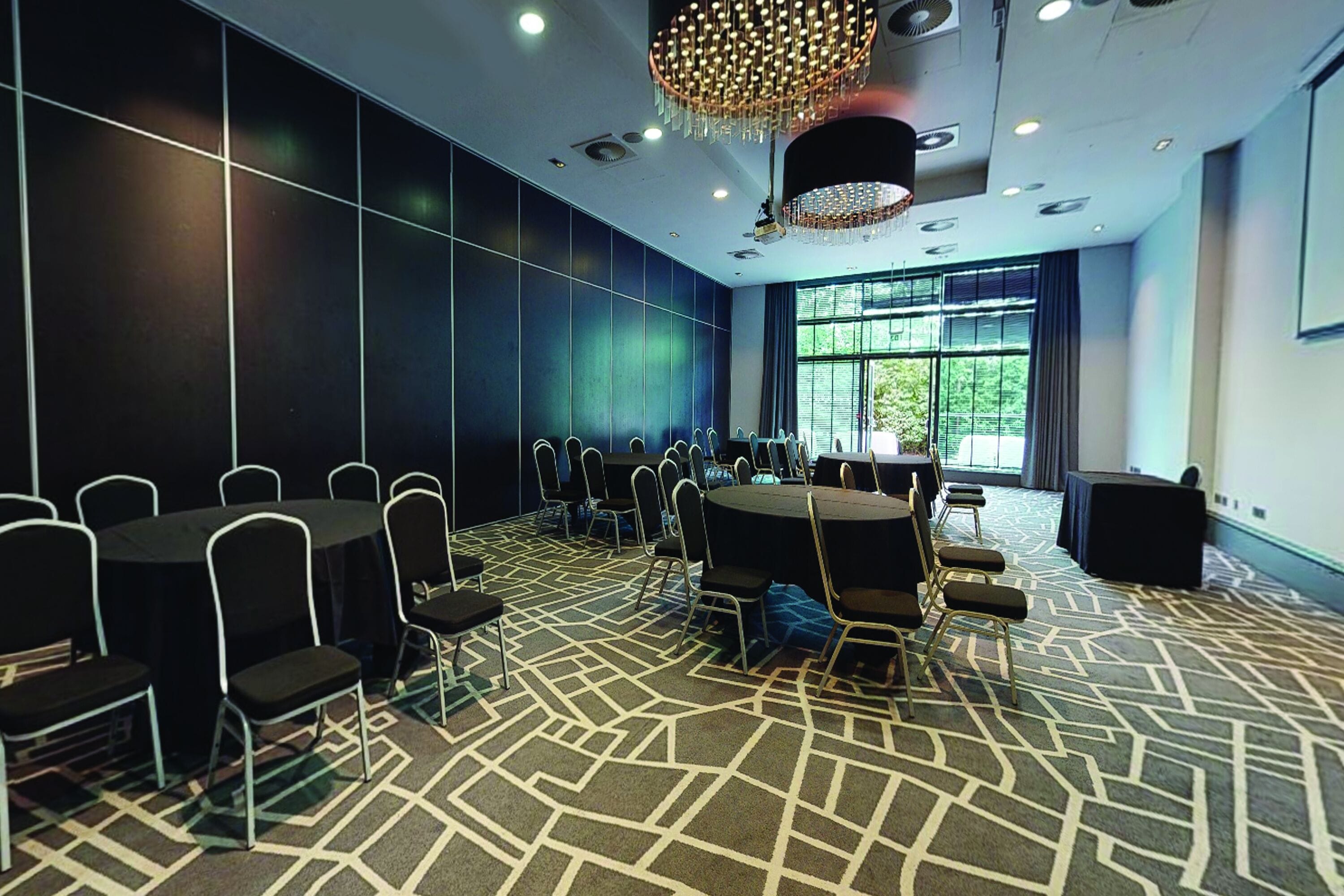 A conference room with a patterned carpet, round tables, and chairs.
