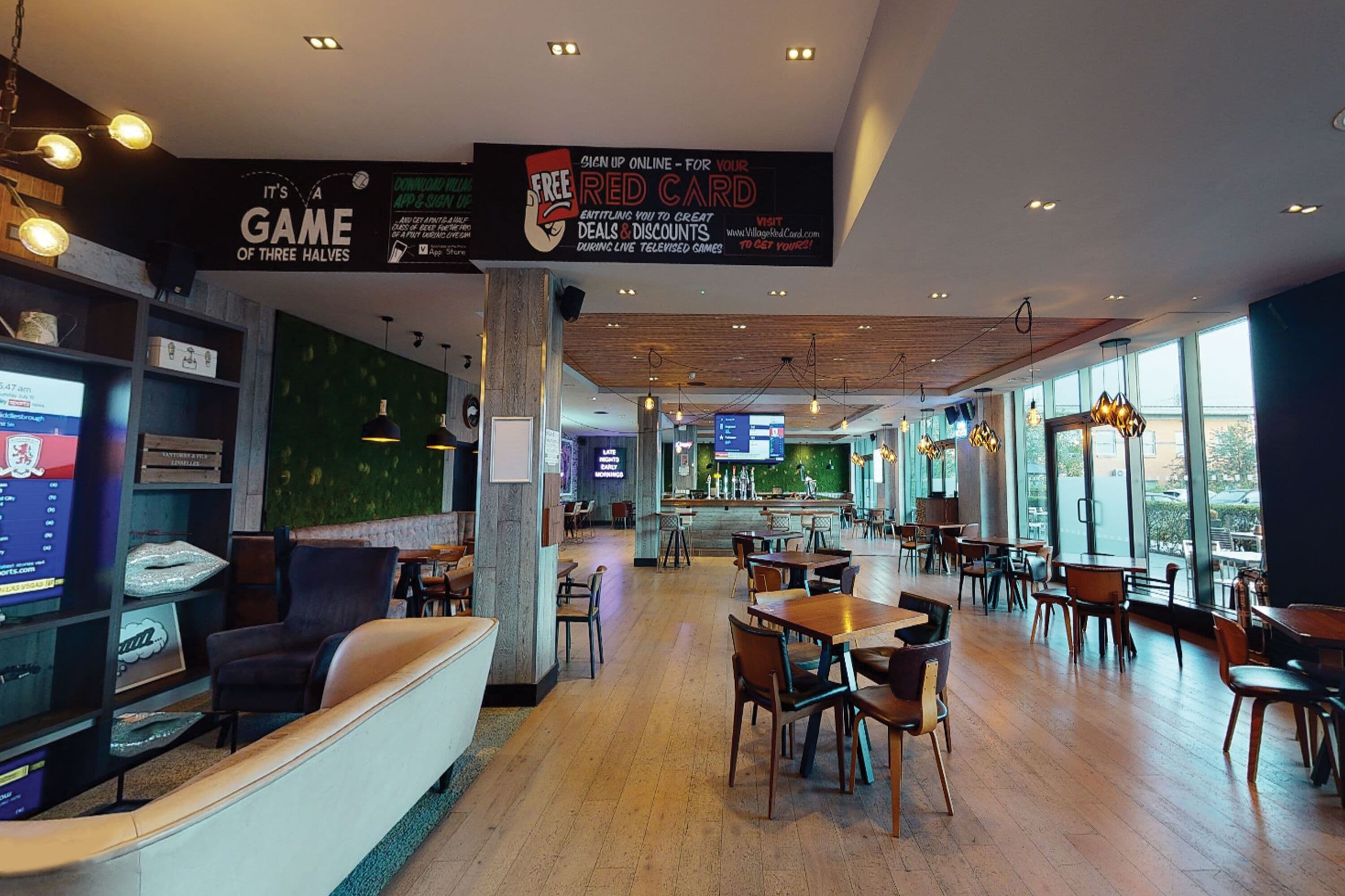 Un restaurante moderno con una barra larga, varias mesas y una zona de bar.