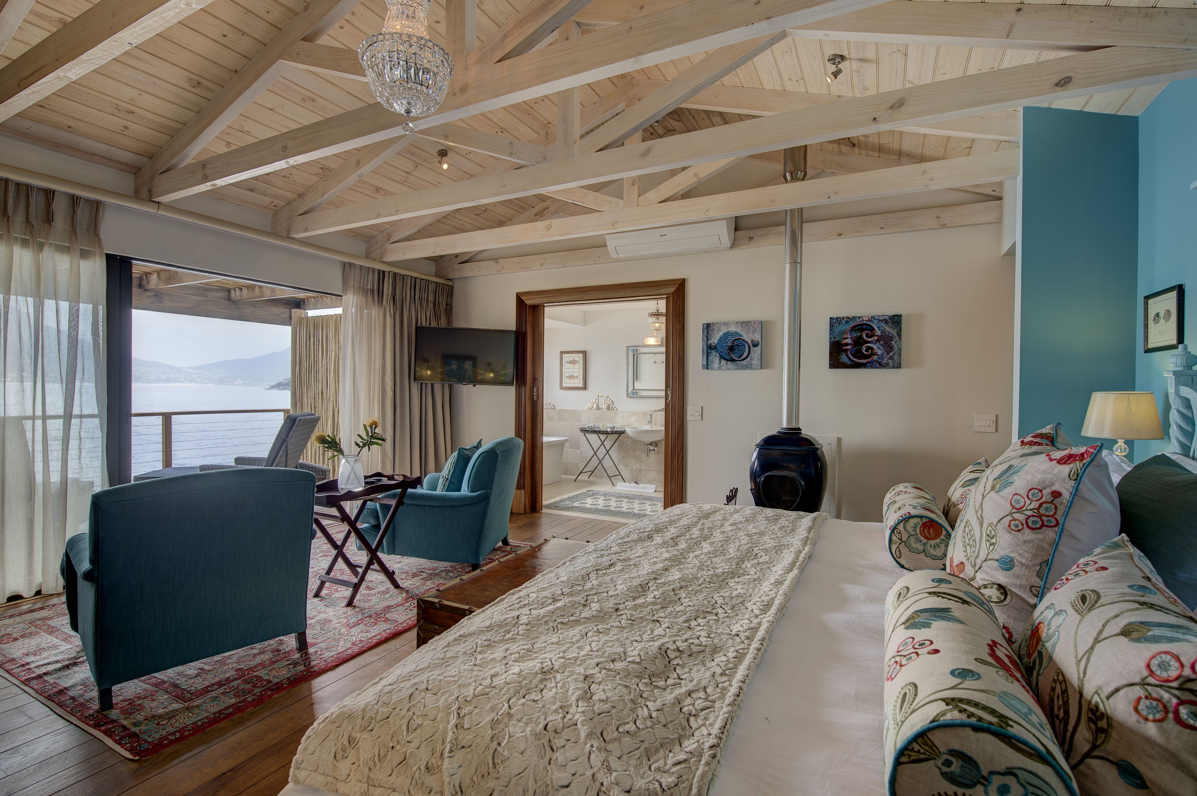 A cozy room with a large bed, a sofa, a chair, and a view of the sea.