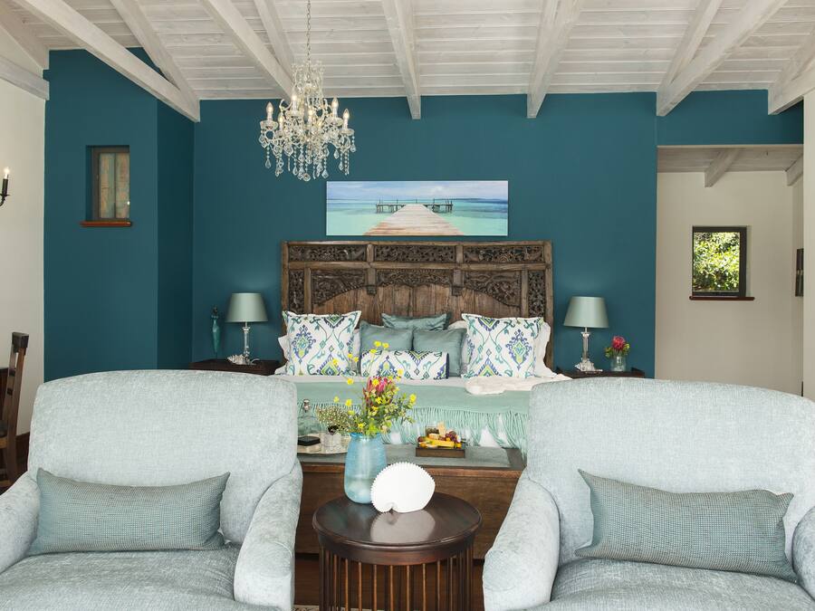 A bedroom with teal walls, a wooden headboard, a chandelier, and a large window.