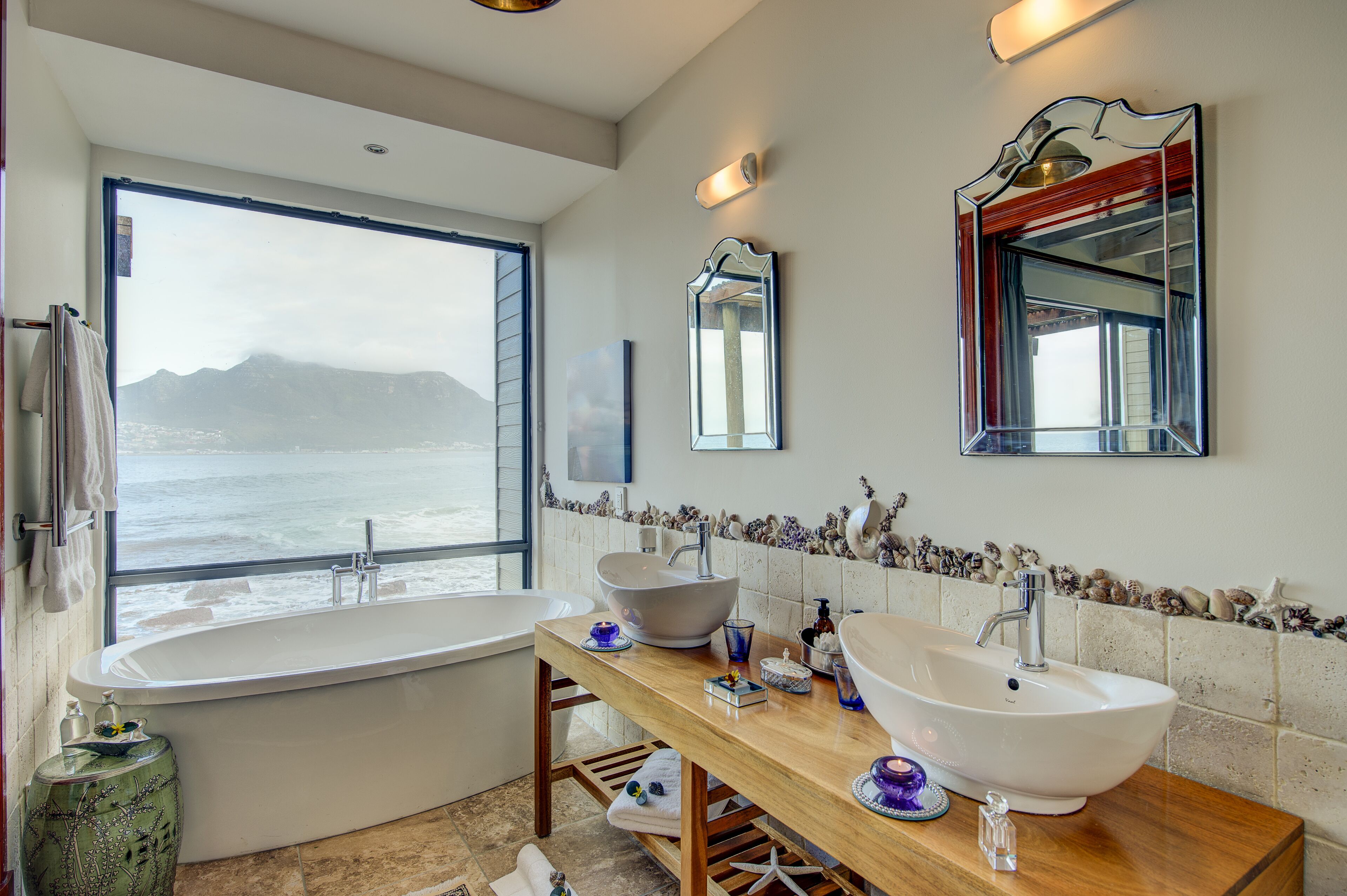 Un baño con bañera, lavabo y un amplio ventanal con vistas al mar.