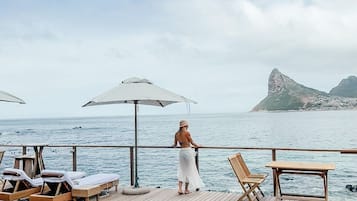 Una piscina al aire libre, sombrillas, sillones reclinables de piscina