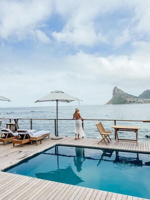 Alberca al aire libre, sombrillas en la alberca y camastros