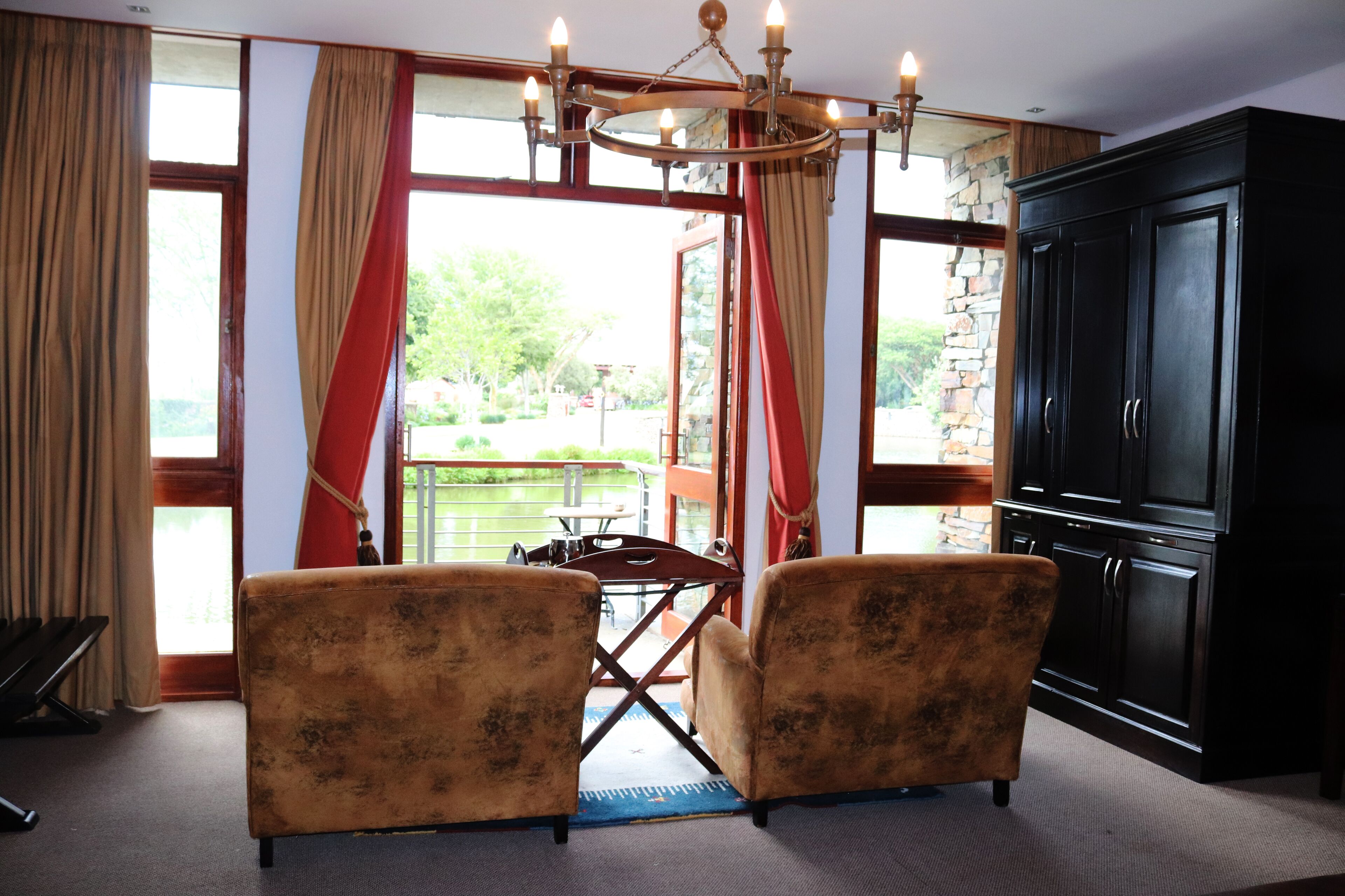 Una habitación con dos sillones, una mesa de comedor y un mueble negro grande.