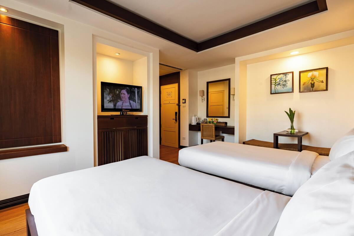 A hotel room with two beds, a TV, a desk, and a chair.