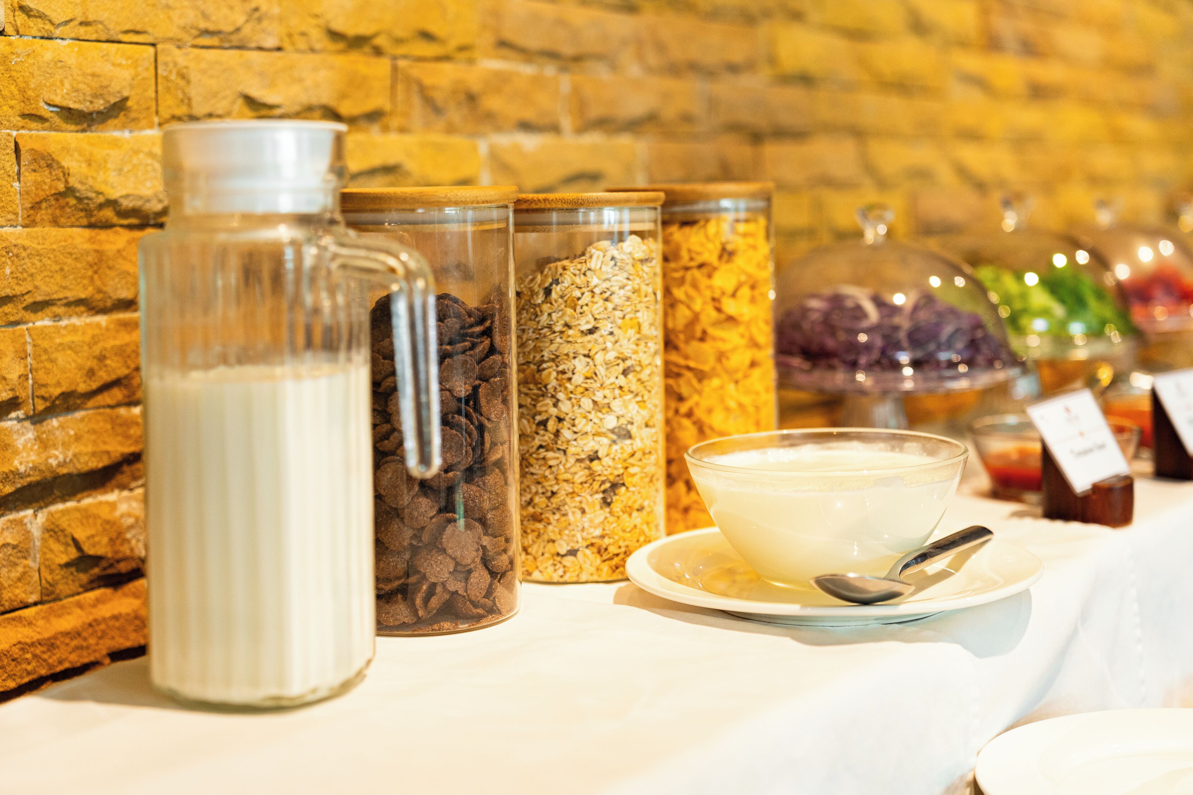 A breakfast buffet with various food items and a milk jug.
