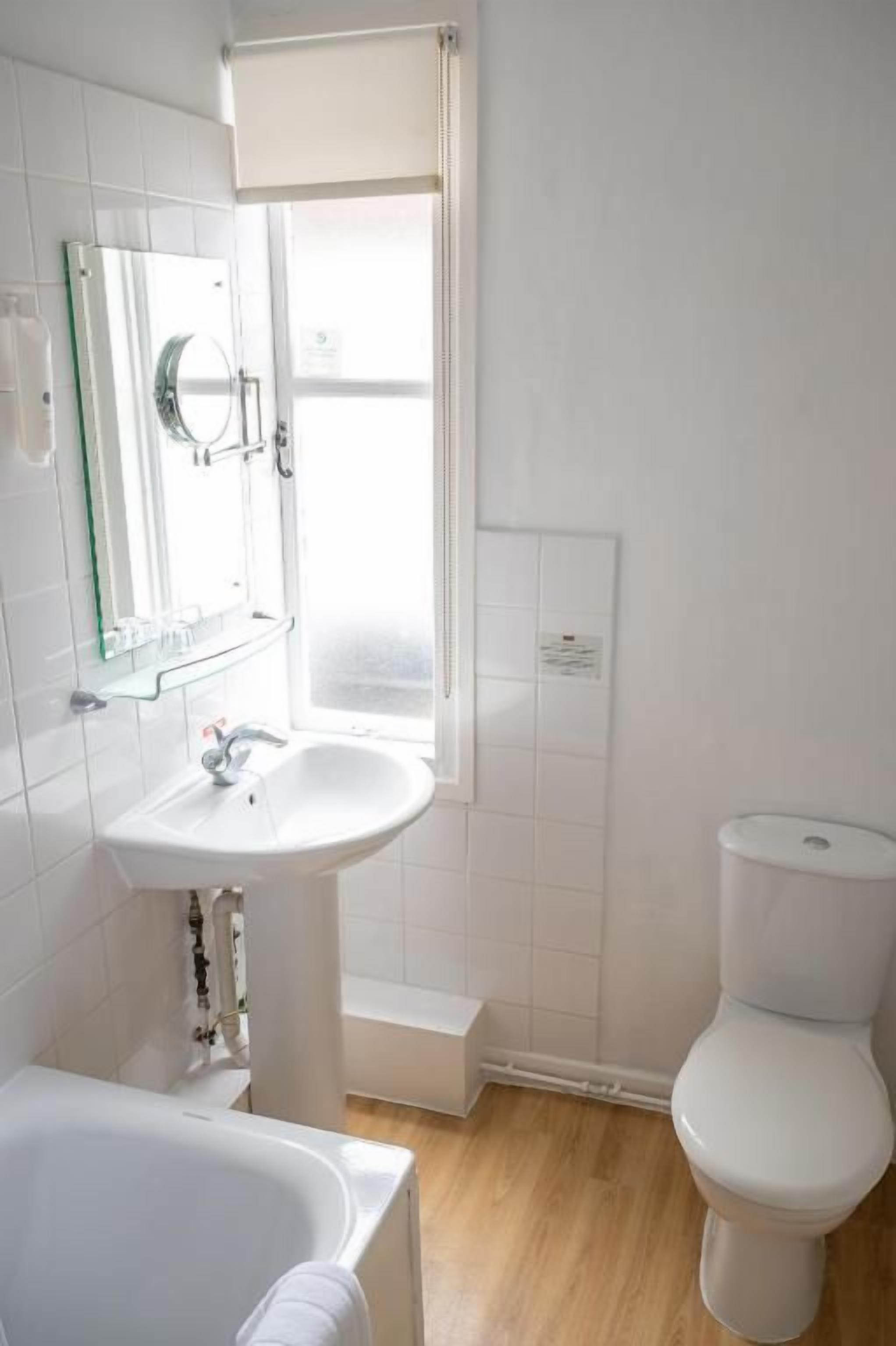 Een badkamer met een wit wastafelmeubel, toilet en een bad.