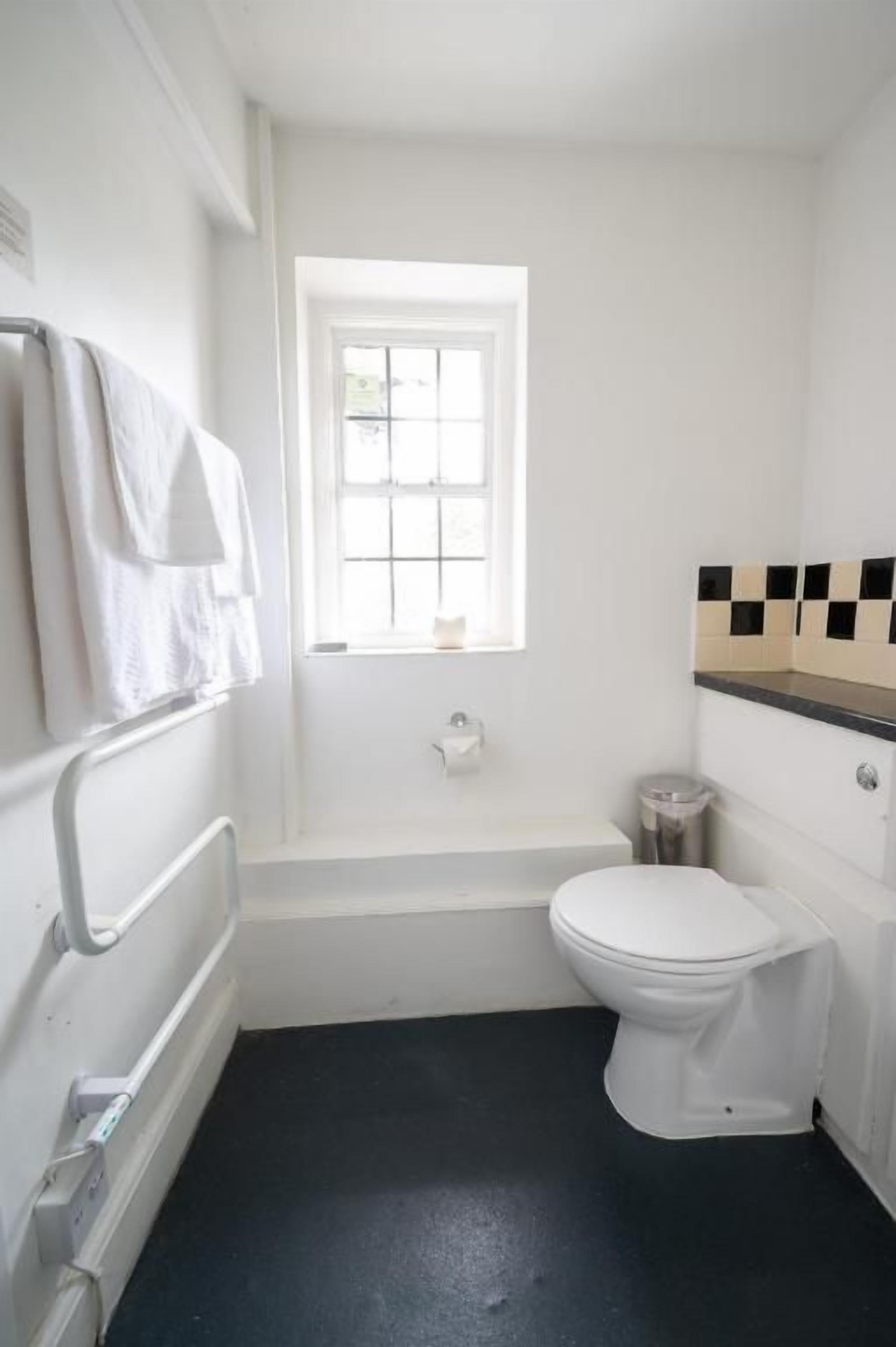 A small, white bathroom with a bathtub, toilet, and a window.