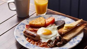 A plate of breakfast food including eggs, sausages, beans, tomatoes, and toast.