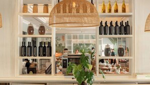 A restaurant interior with shelves of wine bottles, a central table with a plant, and a visible kitchen area. - The Buenaventura Golf & Beach Resort Panama, Autograph Collection (El Chiru)