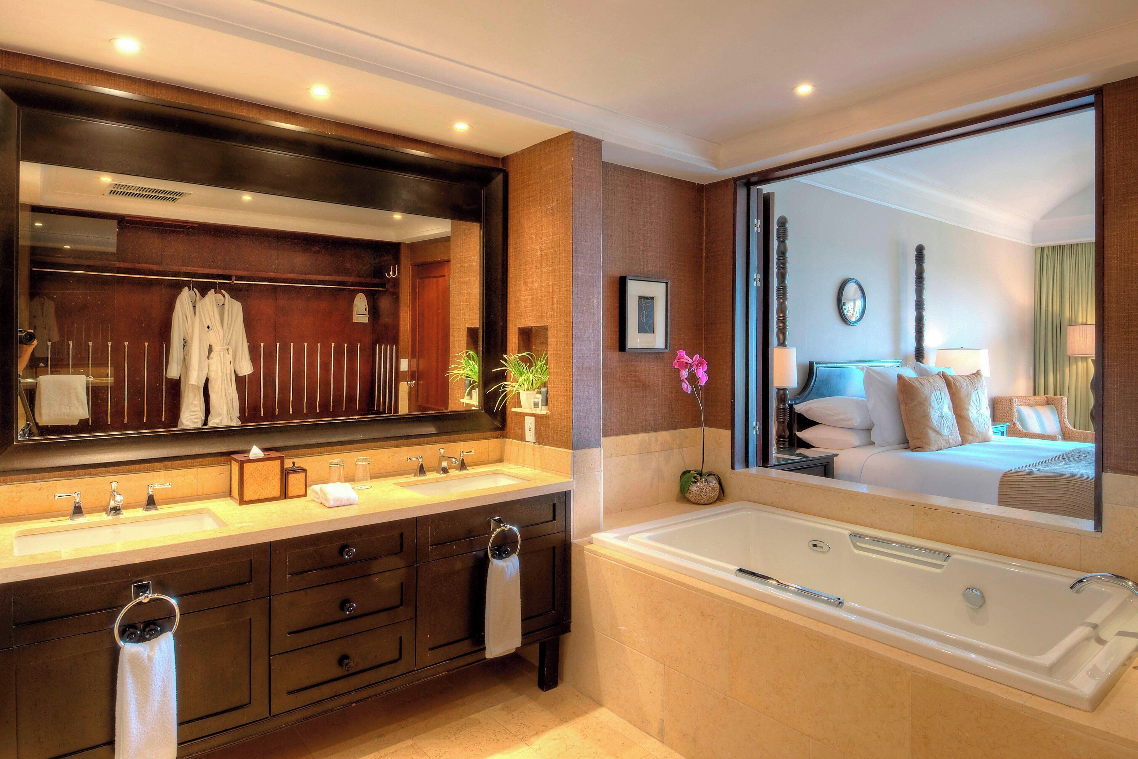 Une salle de bain moderne avec deux vasques, un grand miroir et une baignoire séparée.