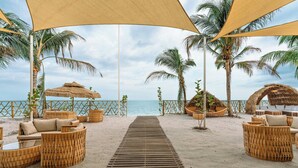 A beachside lounge with wicker furniture, a wooden walkway, and palm trees. - The Buenaventura Golf & Beach Resort Panama, Autograph Collection (El Chiru)