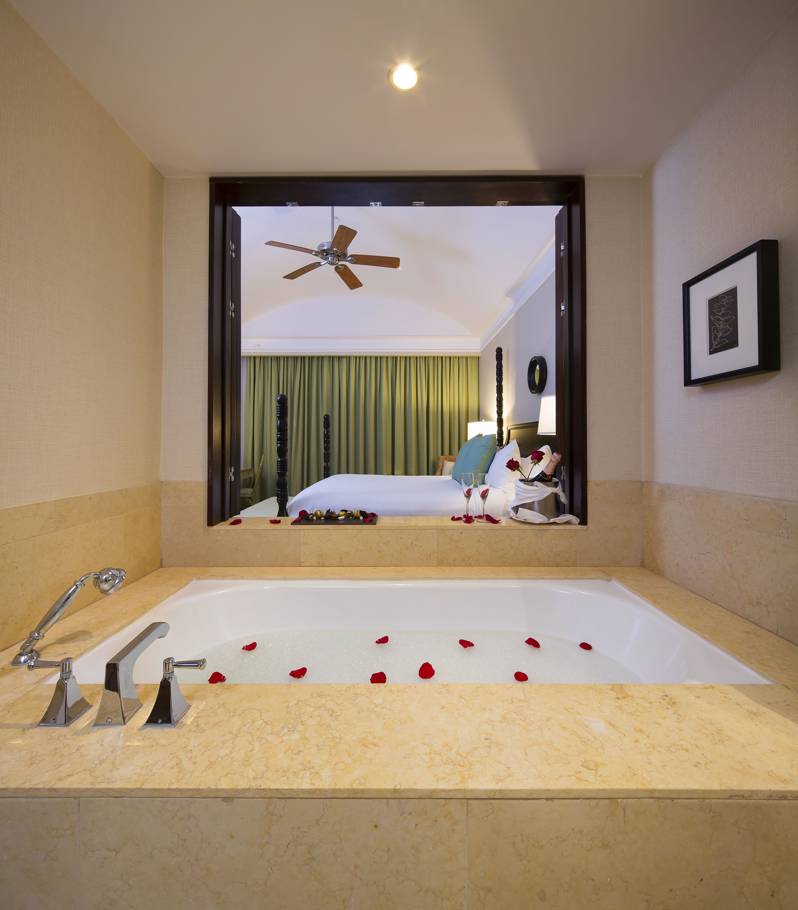 Un baño con una bañera grande, un ventilador de techo y un cuadro en la pared.