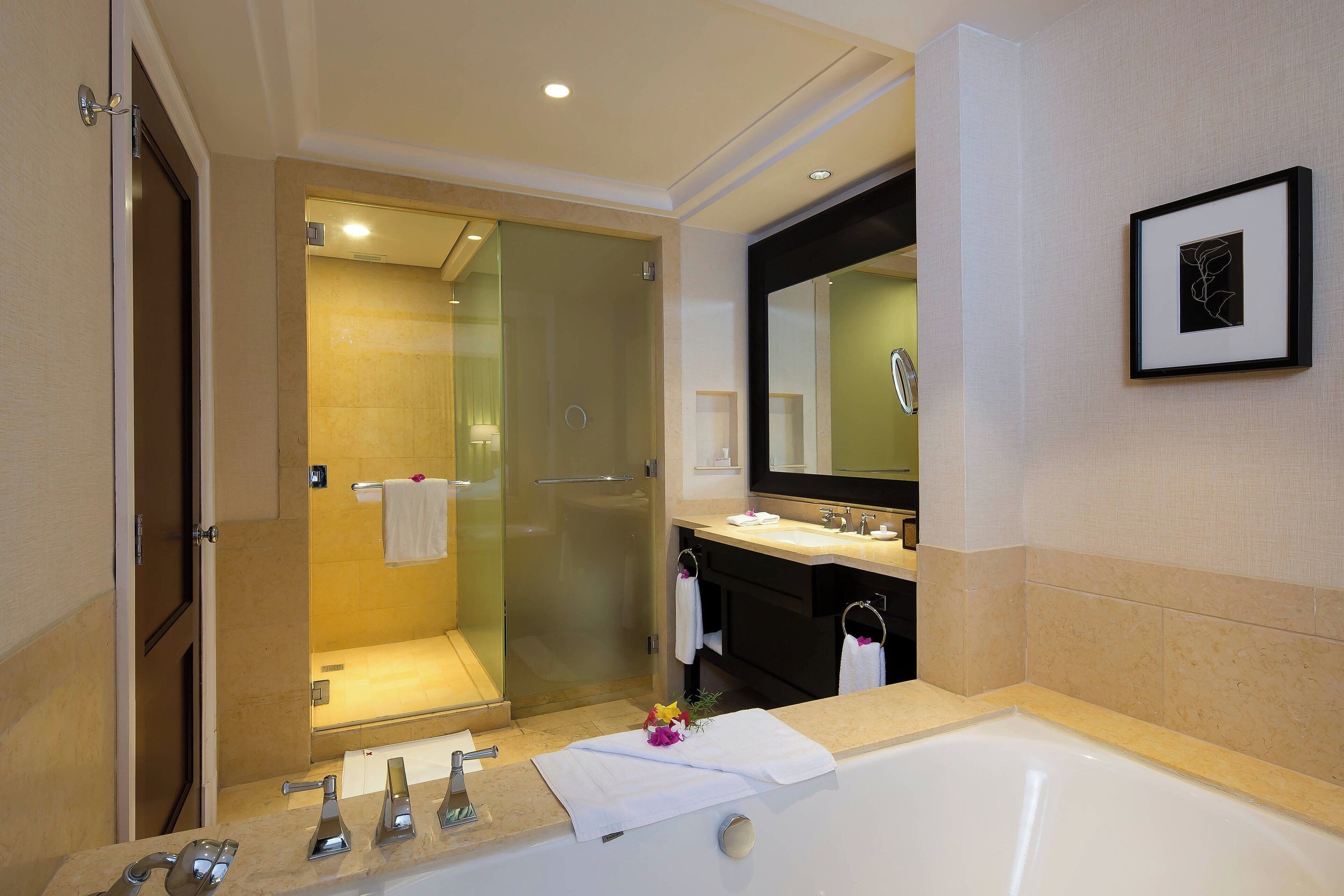 Een moderne badkamer met een ruime badkuip, een douche met glazen wand en een wastafel met spiegel.
