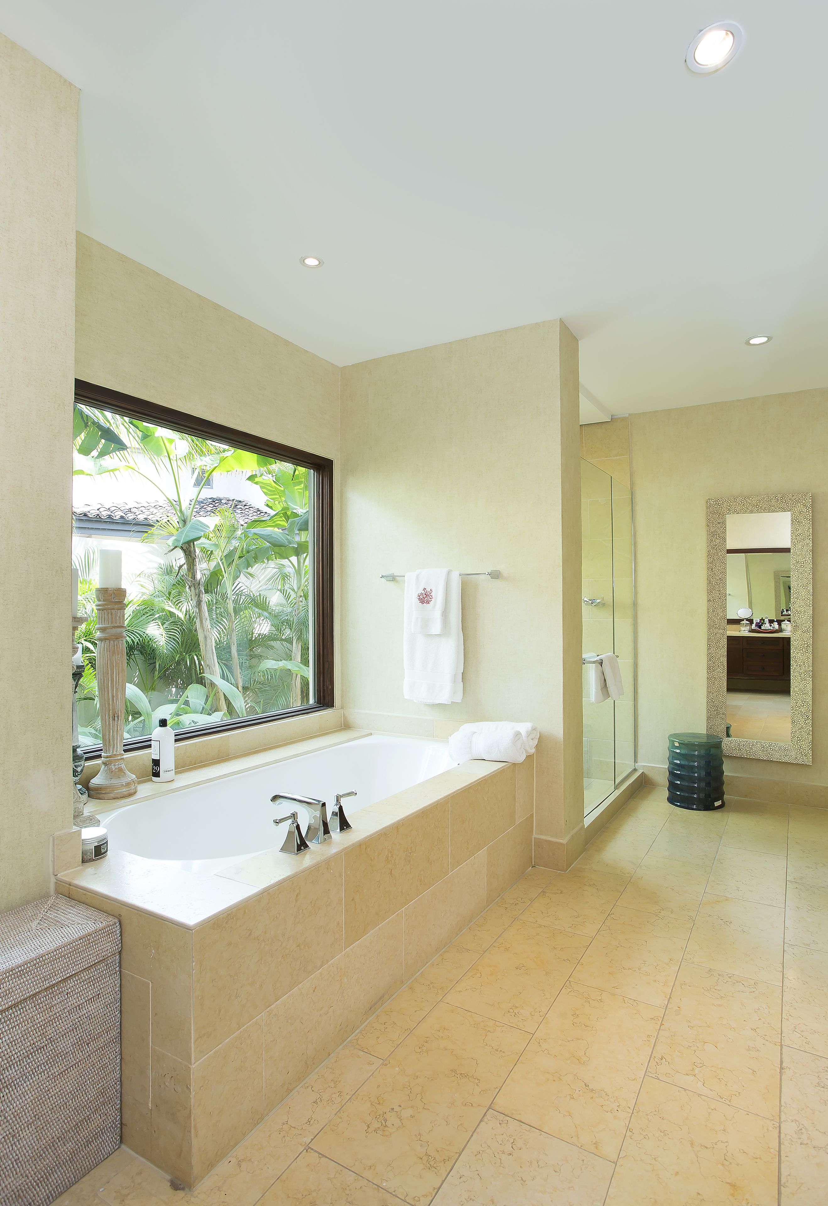 Une salle de bain moderne dotée d’une grande baignoire, d’une douche à parois de verre et d’une fenêtre donnant sur un paysage verdoyant.