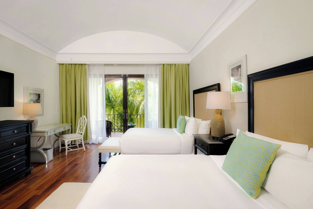 A hotel room with a large bed, a desk, a chair, and a view of the outdoors.