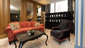 A room with a red sofa, a black armchair, a small table with plants, and a bookshelf with books.