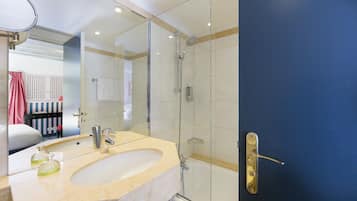 A modern bathroom with a glass-enclosed shower, a sink with a beige countertop, and a mirror above it.