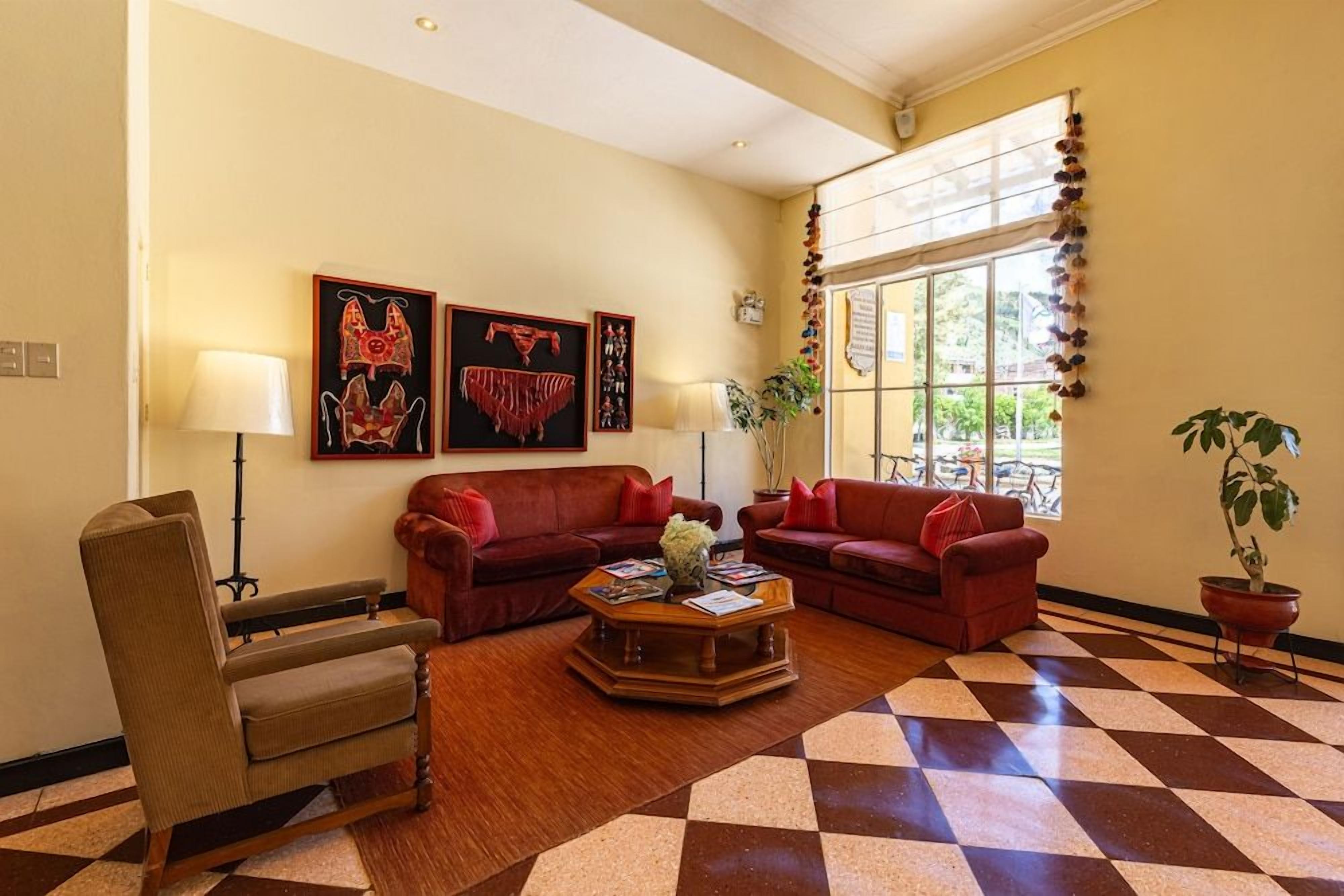 A living room with two red sofas, a wooden coffee table, a brown armchair, and a large window with a view.