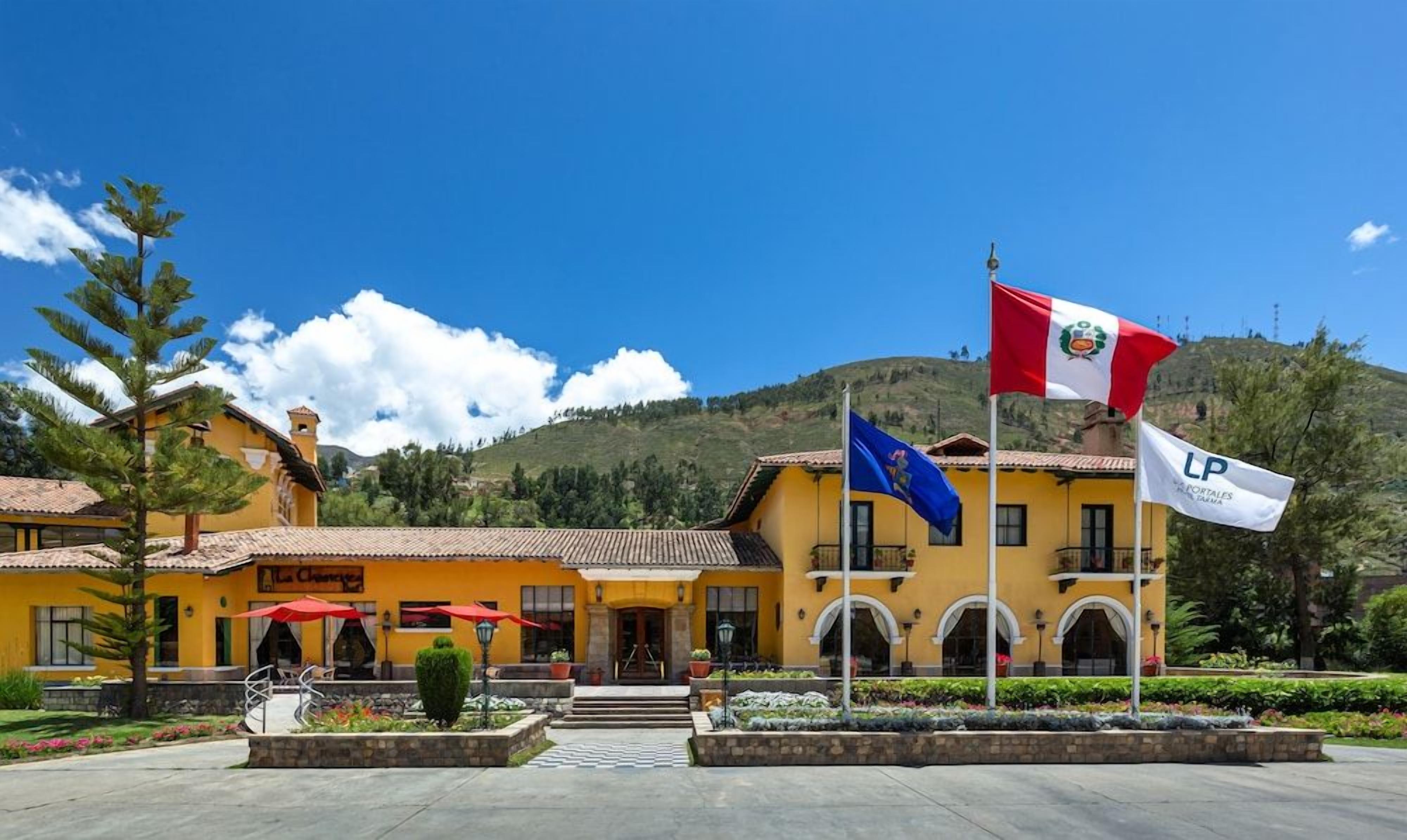 Un hotel con fachada amarilla, una bandera europea y una bandera con escudo de armas.